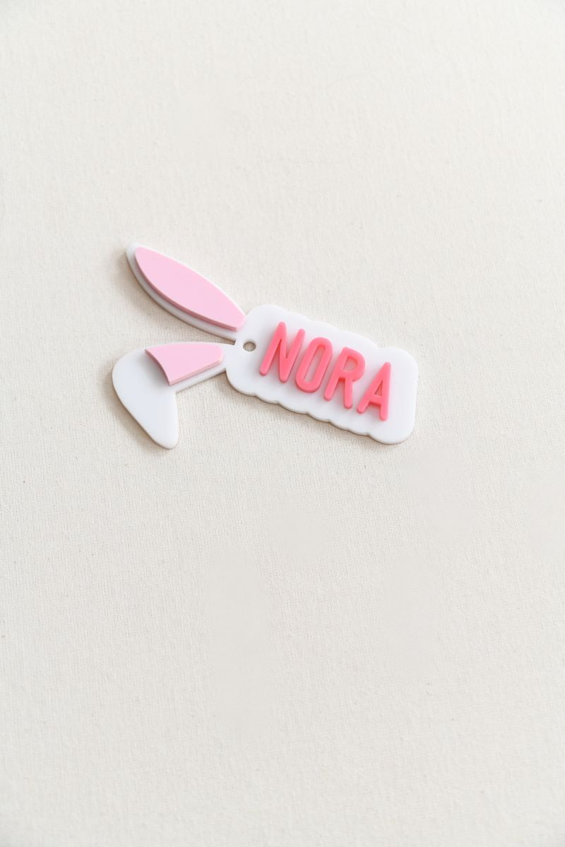 Custom bunny ear gift tag. custom name in your choice of pink, blue, or green, with soft light pink-filled ears for a sweet and festive look.