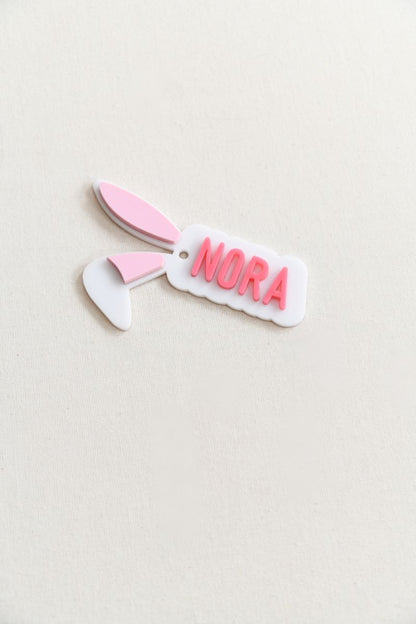 Custom bunny ear gift tag. custom name in your choice of pink, blue, or green, with soft light pink-filled ears for a sweet and festive look.