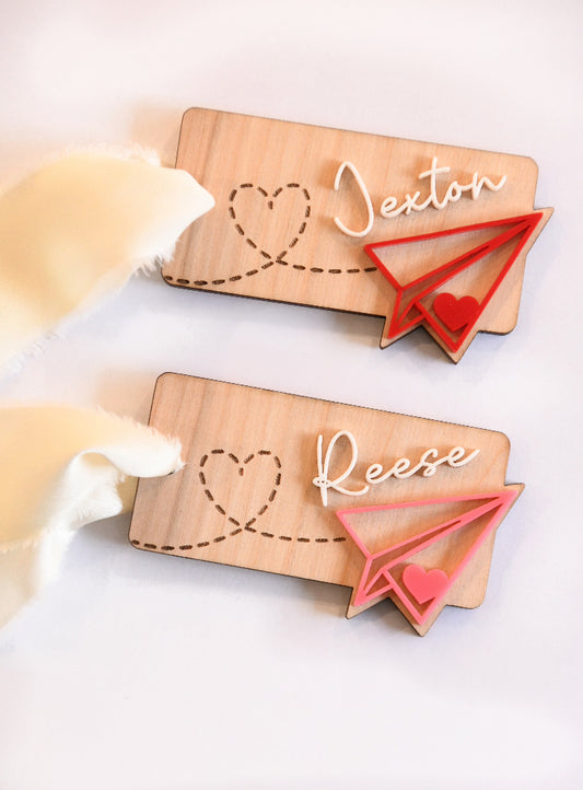 
Custom name wood and acrylic Valentines Day name tag. Paper airplane leaving a heart path behind it. With elegant white ribbon to tie to any item or gift.

